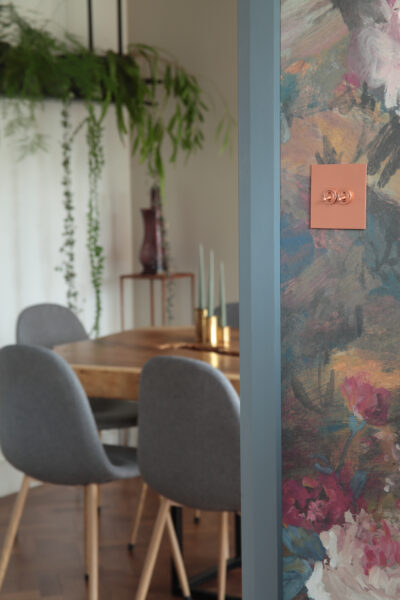 Lightswitch on wall with floral wallpaper with dining room behind